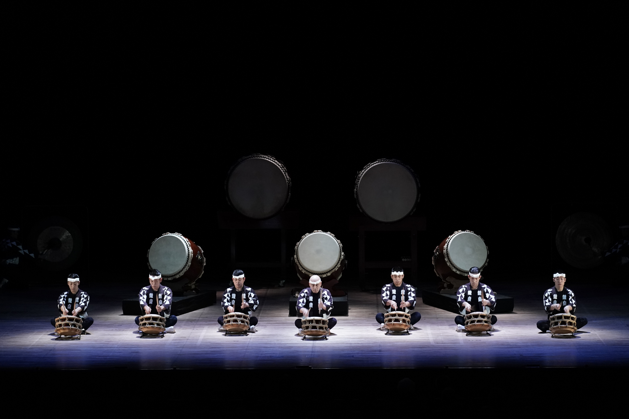 Img:Japanese drummers on a darkened stage
