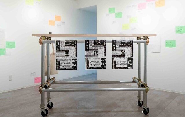 Img:Posters hanging from metal scaffolding on wheels