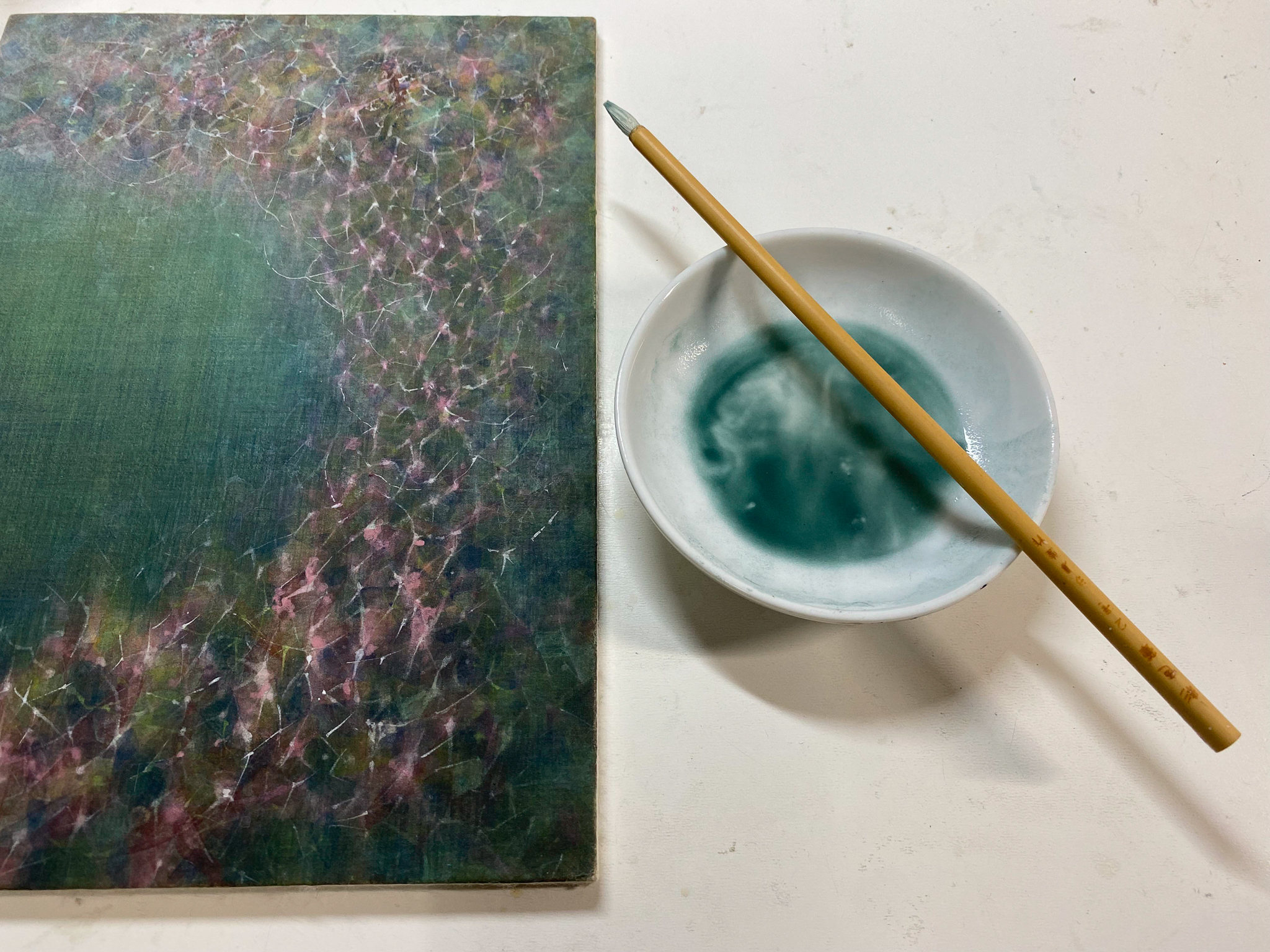 Canvas painting of blue and purple next to a bowl holding watercolour paint