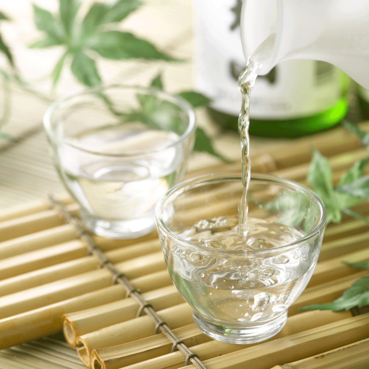 Img:Two glass Sake cuup and pooling cake on the Bamboo try and green