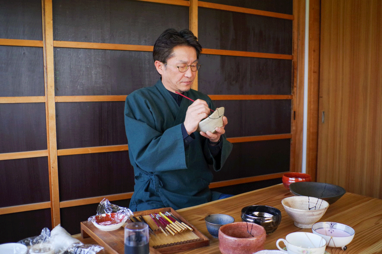 Img:man sitting in his workshop painting tea cups