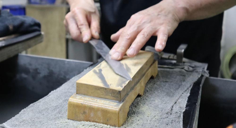 Hands sharpening a knife on a block