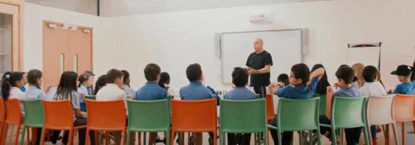 Img:Teacher speaking to a class full of students