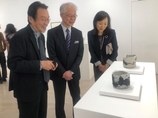 Two man and Woman looking at pottery